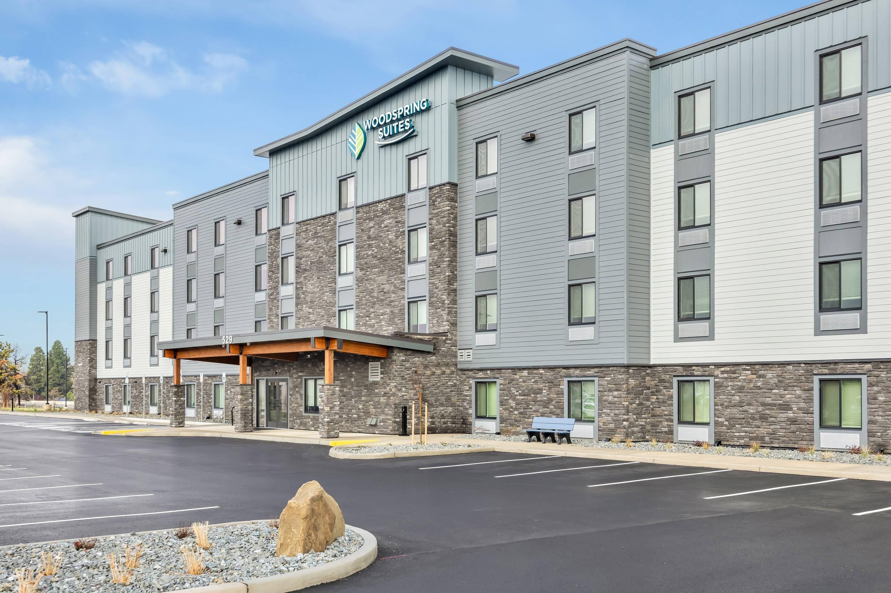 Ein Hotel mit steinverkleideter Fassade, zahlreichen Fenstern und einem Schild mit der Aufschrift "Woodspring Suites".