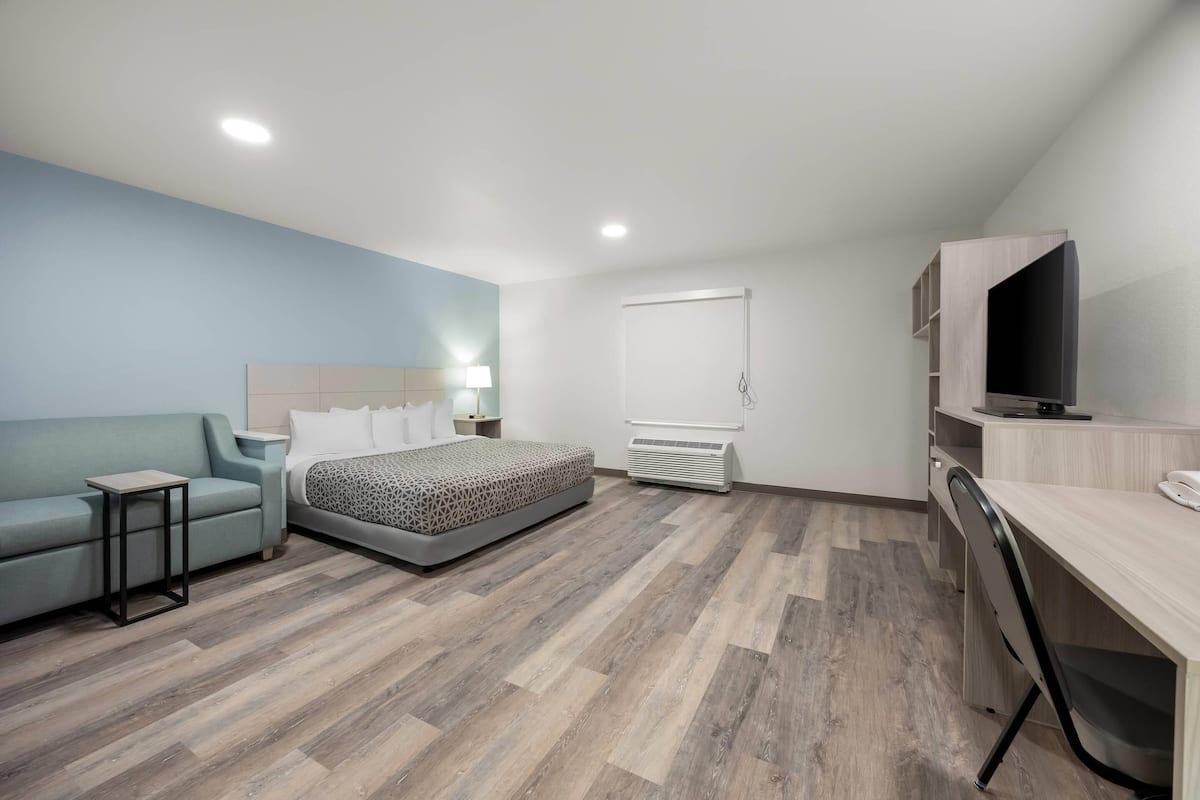 Een moderne hotelkamer met een bed, een bank, een bureau en een televisie.