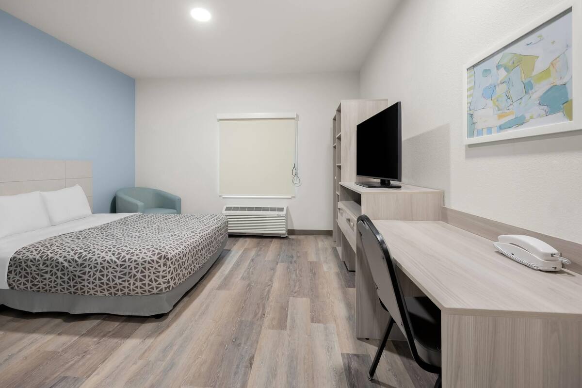 Een hotelkamer met een bed, een bureau, een stoel, een televisie, een telefoon en een raam.