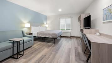 Una habitación de hotel moderna con cama, escritorio, silla, televisor y ventana con persianas.