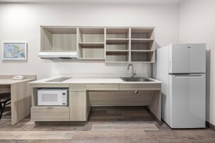 Una cocina moderna con electrodomésticos integrados, encimera de madera y refrigerador blanco.