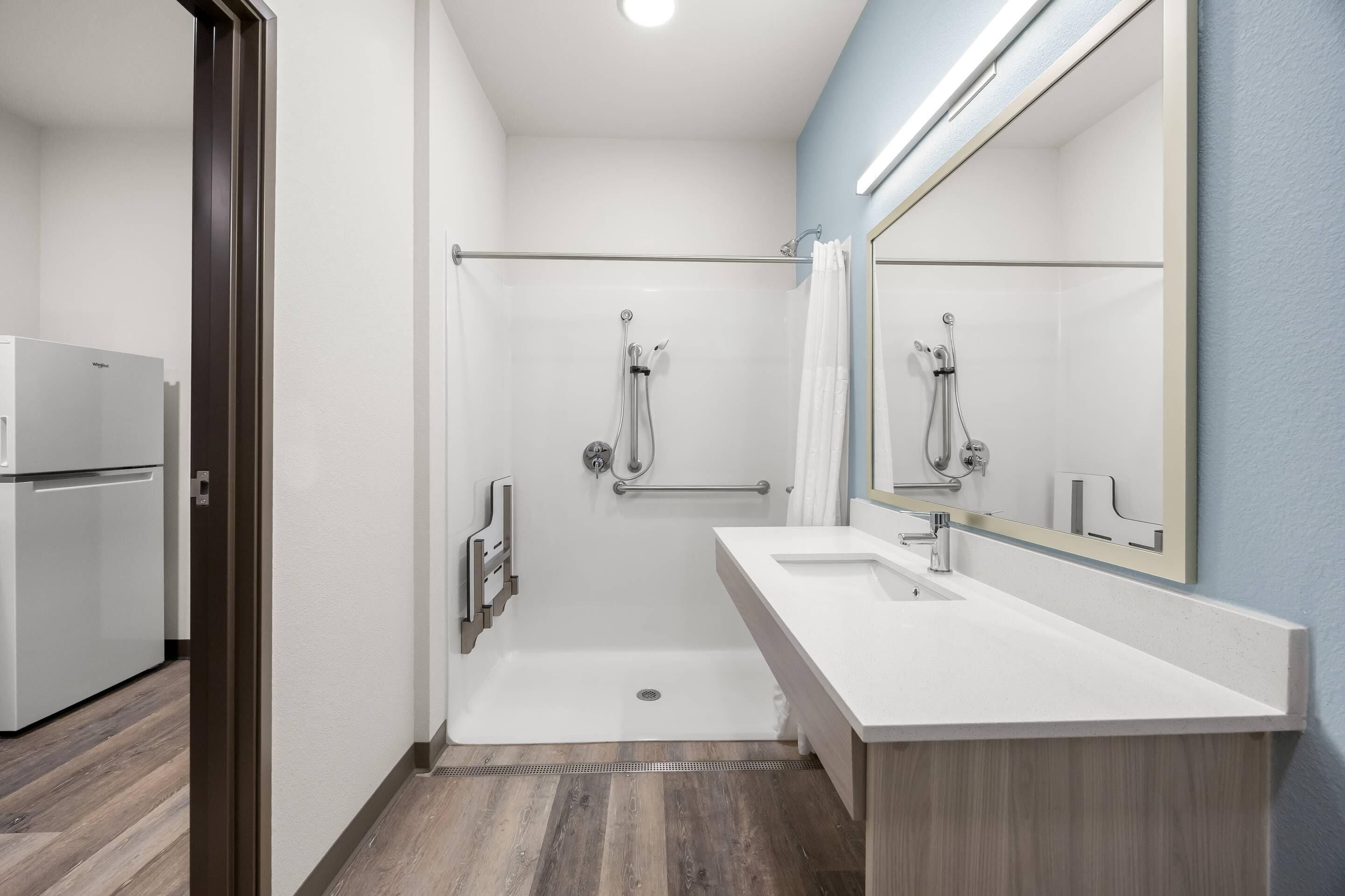 Un baño moderno con cabina de ducha, un lavabo blanco y un espejo grande.