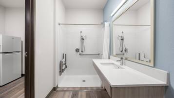 Un baño moderno con cabina de ducha, un lavabo blanco y un espejo grande.