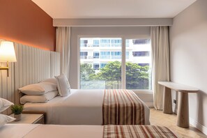 A hotel room with a large bed, bedside tables, a window with curtains, and a view of buildings and trees outside. - Faranda Collection Cartagena, a member of Radisson Individuals (Cartagena)