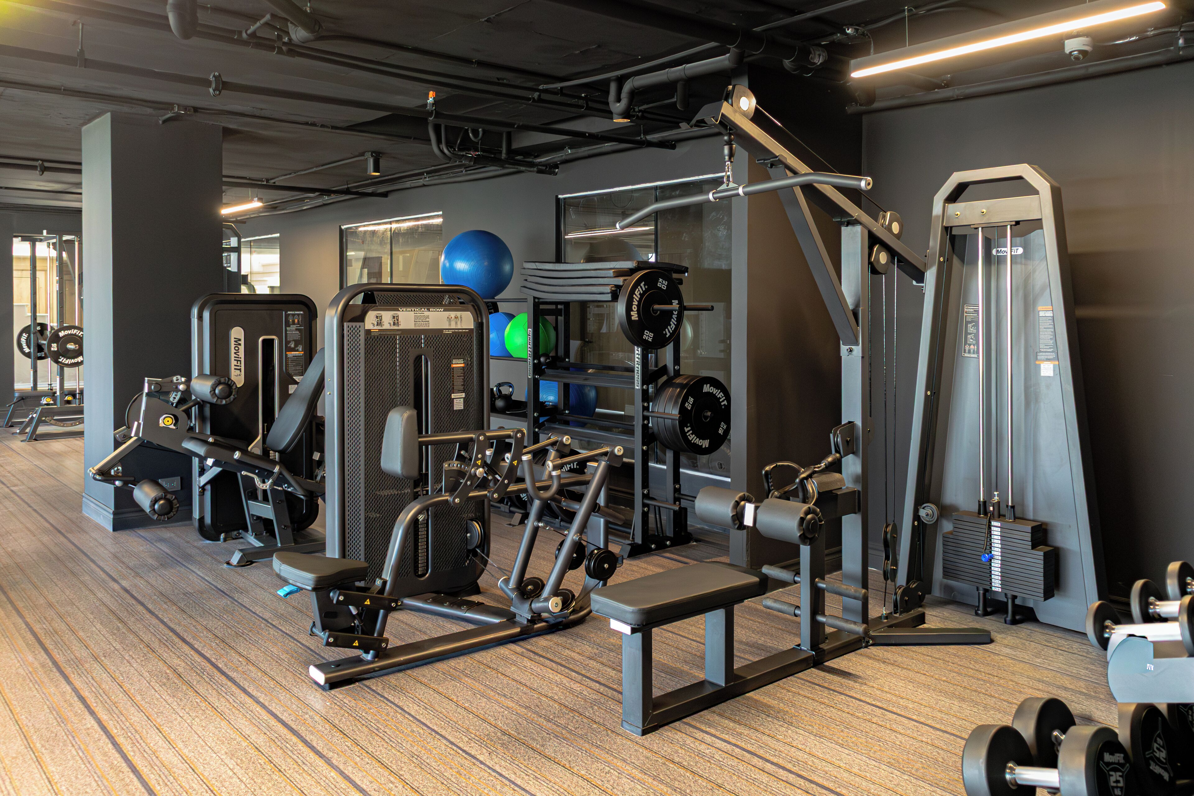A gym with various exercise equipment, including weight machines, free weights, and cardio machines.