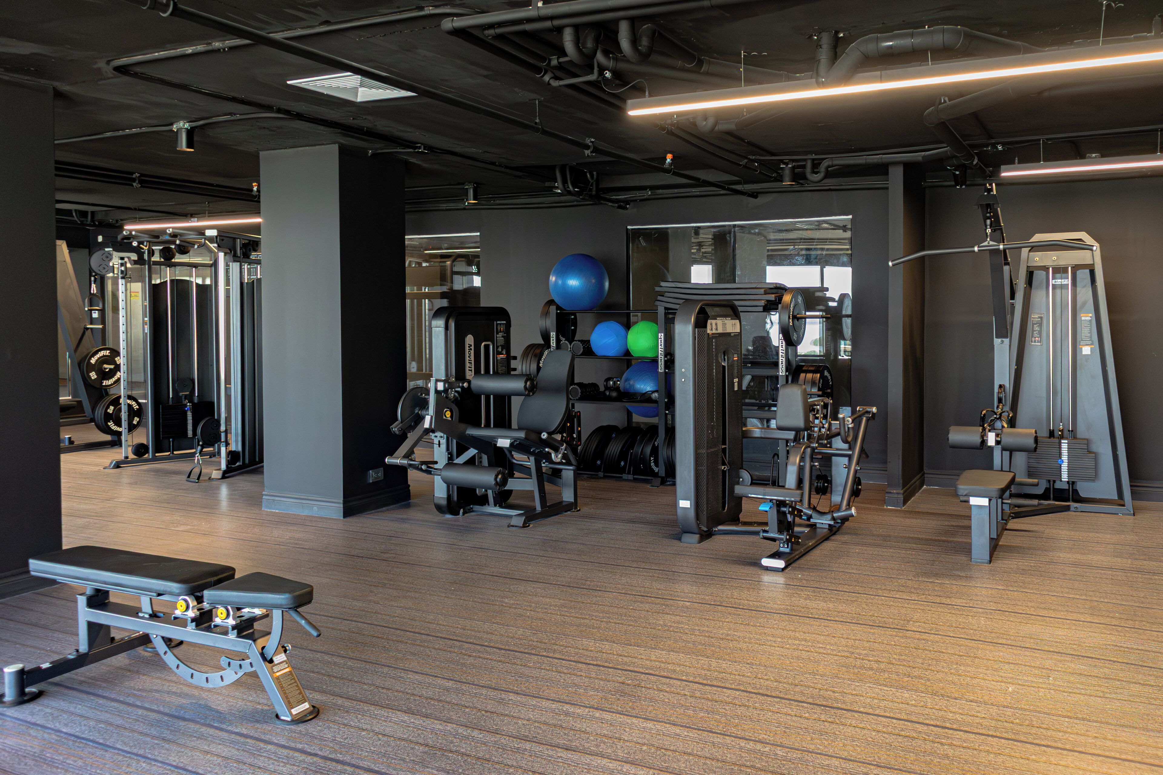 Et fitnesscenter med forskellig træningsudstyr, en bænk og vægtløftningsmaskiner.