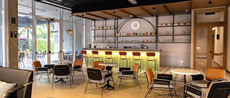 Un área de bar moderna con mostrador, asientos y estantes con objetos.