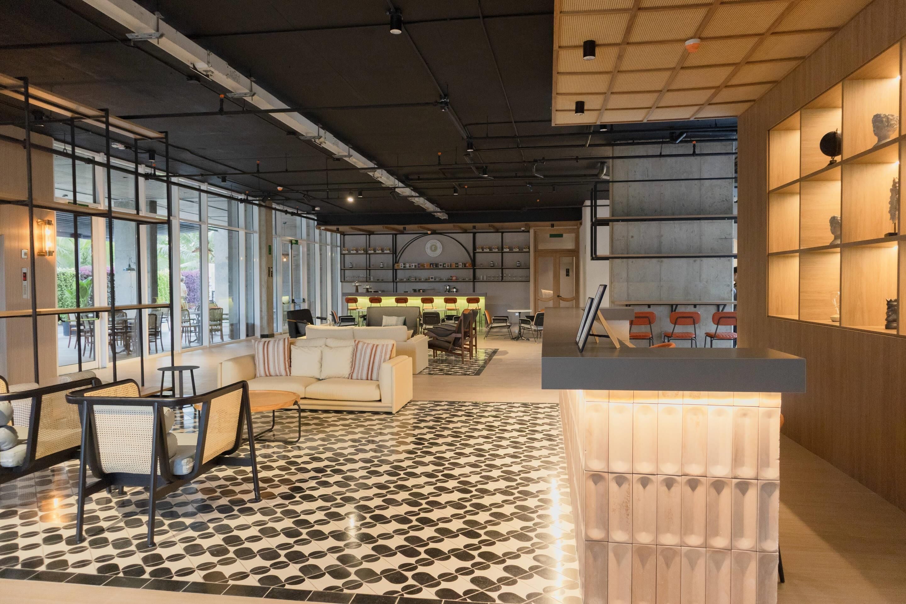 A modern interior with a seating area, a reception desk, and a display of items on shelves.