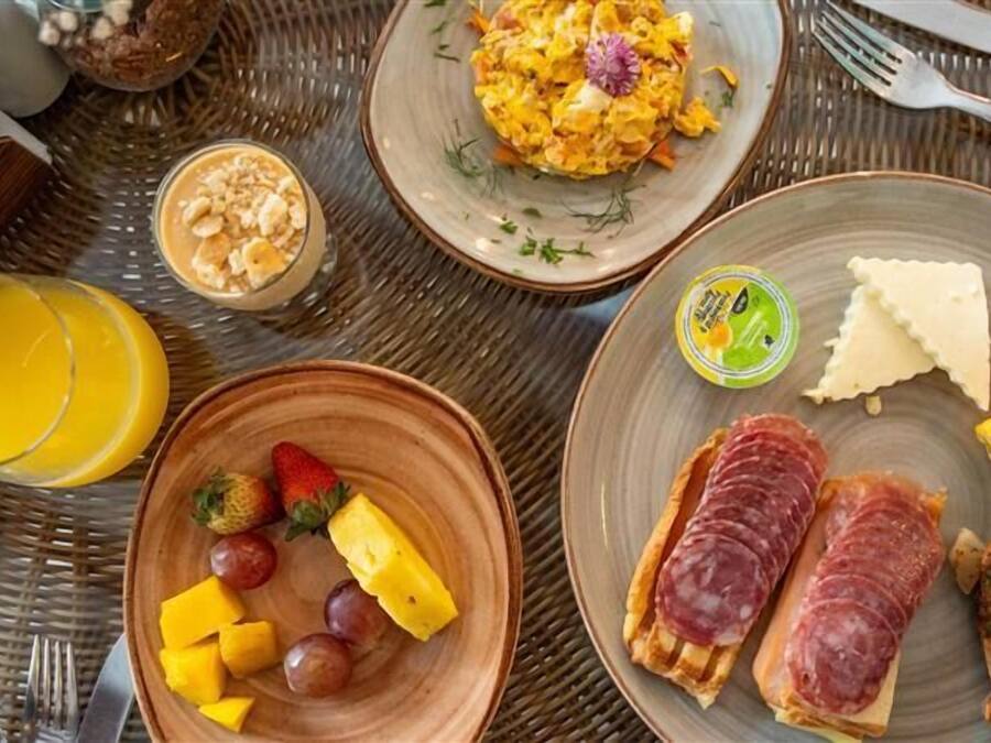 A breakfast setting with plates of scrambled eggs, toast, and fruit, including grapes and pineapple.