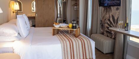 A hotel room with a bed, bedside table, TV, and a view of the outdoors.