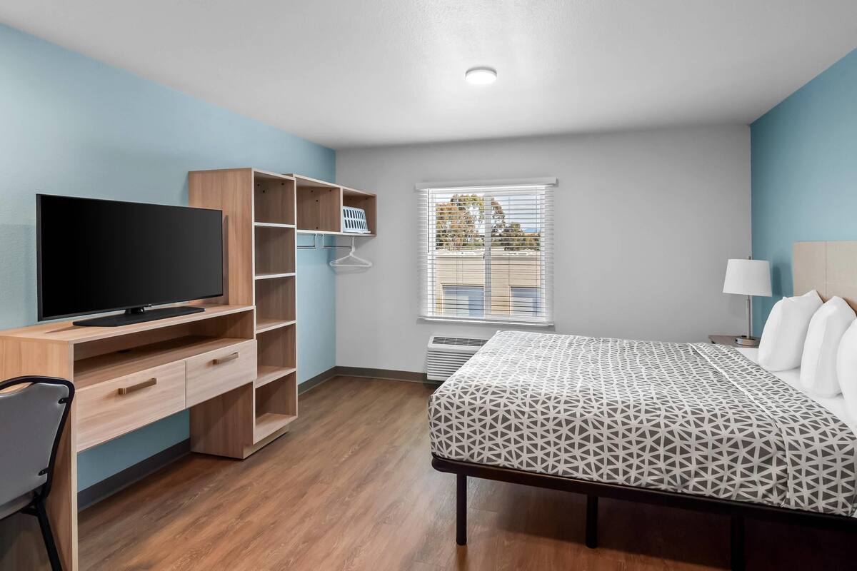 A bedroom with a bed, a TV, a desk, and a wardrobe.