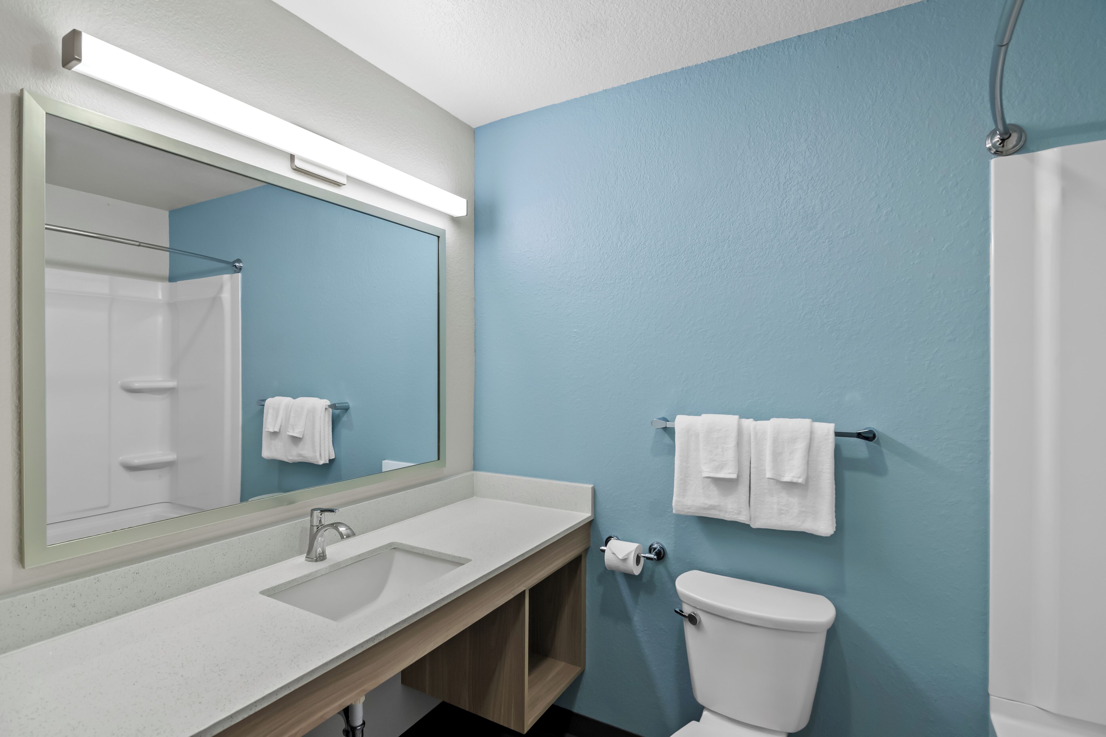 A bathroom with a sink, mirror, toilet, and towel rack.