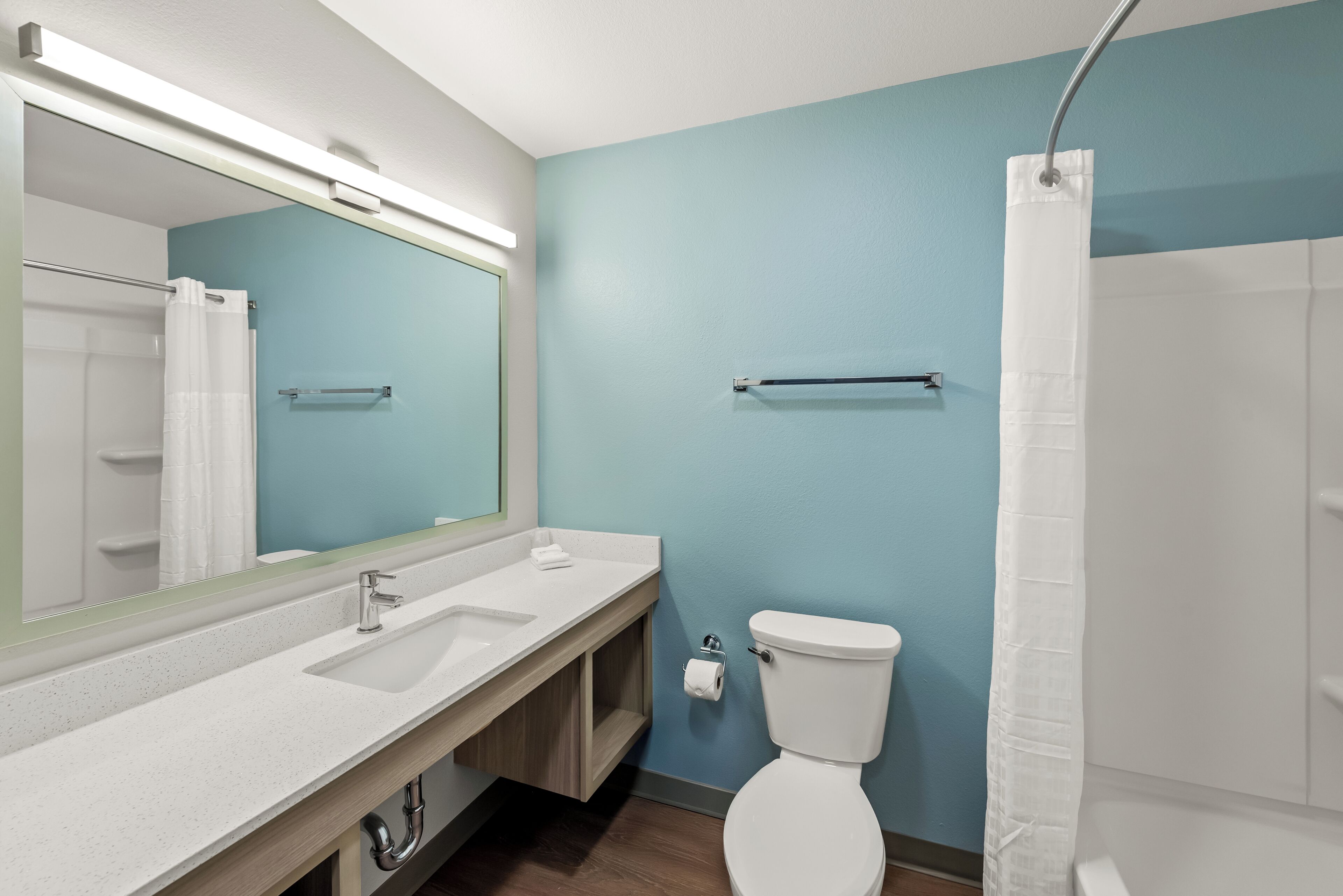 A bathroom with a white sink, a mirror, a toilet, and a shower curtain.