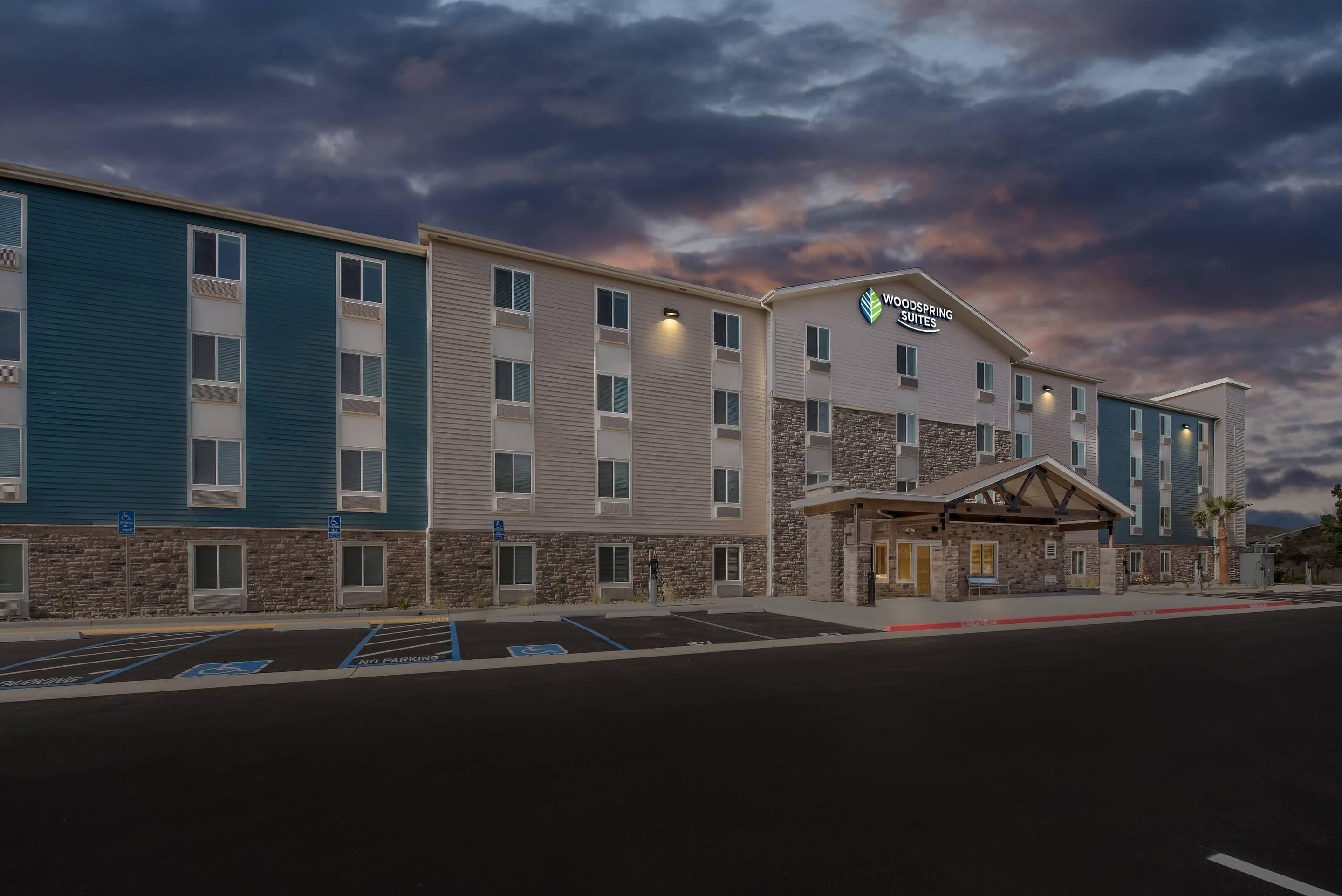 Um hotel com fachada de pedra, vários andares e uma placa indicando "Woodspring Suites".