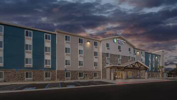 Um hotel com fachada de pedra, vários andares e uma placa indicando "Woodspring Suites".