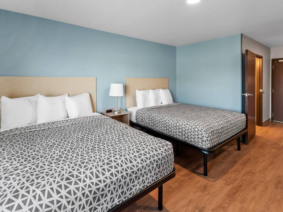 Una habitación de hotel con dos camas, una mesita de noche, una lámpara y una puerta de madera.
