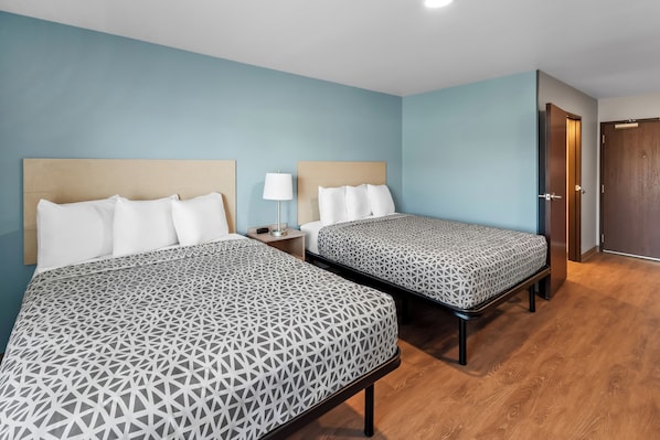 Una habitación de hotel con dos camas, una mesita de noche con lámpara y una puerta de madera.