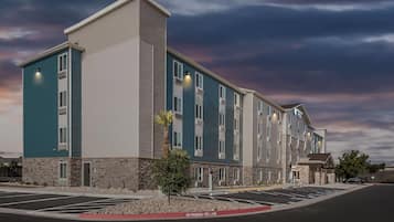 A multi-story hotel with a modern design, featuring a mix of stone and siding exteriors, and a parking lot with marked spaces.