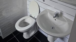 Une salle de bain moderne équipée de toilettes, d’un lavabo et d’un miroir au-dessus du lavabo.
