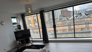 Un salon moderne avec une grande fenêtre, un téléviseur à écran plat et un canapé.