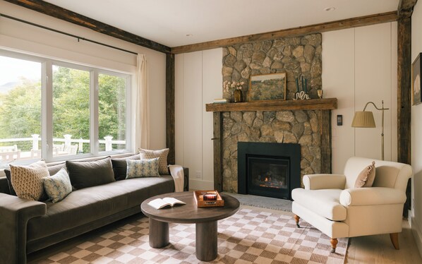A living room with a stone fireplace, a sofa, a chair, and a coffee table.