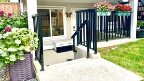 A residential house with a covered porch, a staircase, and a garden with potted plants. - Brand New Haven (Surrey)