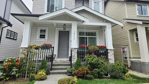 A two-story house with a front porch, a grey door, and a mailbox. - Brand New Haven (Surrey)