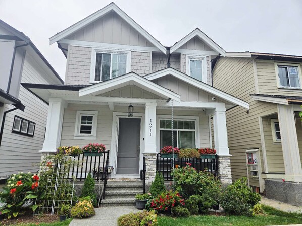 A two-story house with a front porch, a grey door, and a mailbox. - Brand New Haven (Surrey)