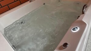 A hot tub with a brick wall background. - POUSADA DECK PEREIRÃO (Santa Terezinha)