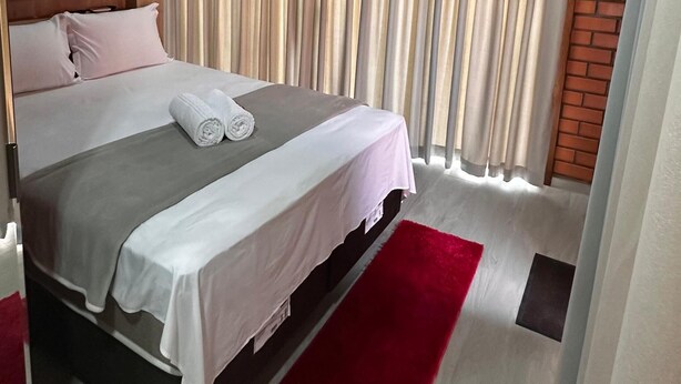 A bedroom with a bed, a red rug, and a canopy. - POUSADA DECK PEREIRÃO (Santa Terezinha)
