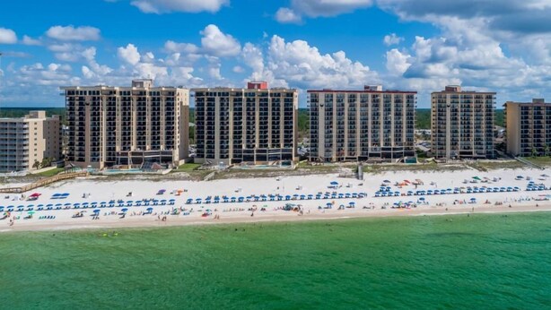 A beachfront hotel with multiple high-rise buildings, a sandy beach, and a clear blue sky.