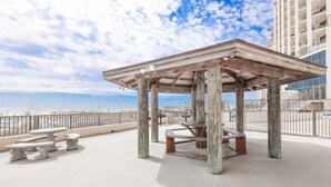A rooftop patio with a wooden gazebo, picnic tables, and a view of the city skyline.