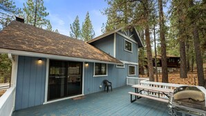 A two-story house with a blue exterior, a covered deck, and a grill.