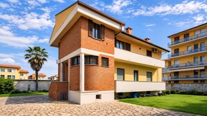 A modern two-story residential building with a brick facade, multiple balconies, and a paved courtyard. - Whole house in Magenta | Business, families, Milan/Rho (Magenta)