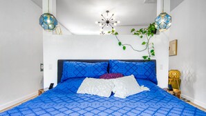 Une chambre à coucher avec un grand lit, un lustre et deux lampes suspendues.