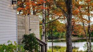 Une maison en bois avec un escalier en pierre menant à une terrasse d’où l’on a vue sur un lac.