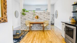 Une cuisine moderne avec un coin repas, agrémentée d’un papier peint à motifs, d’un plancher en bois et d’une décoration contemporaine.