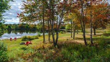 A lakeside view with trees, a grassy area, and a small dock.