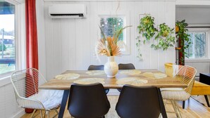 A dining area with a wooden table, six chairs, a vase with dried plants, and a hanging plant. - Forest cottage on the lake ☀️ (Fairfield)