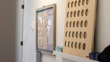 Un gioco da tavolo Scrabble disposto su un muro, un pannello di legno con aperture circolari e un termosifone sottostante.