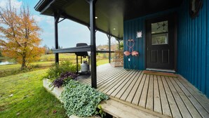 A covered porch with a gas grill, a bench, and a planter with green foliage. - Forest cottage on the lake ☀️ (Fairfield)