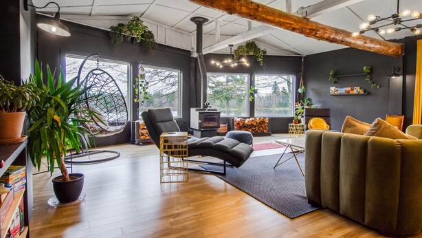 A modern living room with a fireplace, wooden beams, and large windows. - Lakeside Lodge Bay of Fundy (Fairfield)