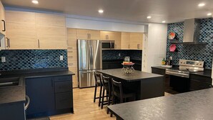 A modern kitchen with wooden cabinets, stainless steel appliances, and a black countertop. - Lakeside Lodge Bay of Fundy (Fairfield)