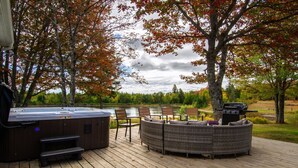 A wooden deck with a hot tub, outdoor seating, and a grill. - Lakeside Lodge Bay of Fundy (Fairfield)