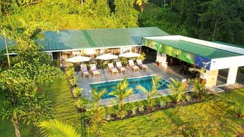 A resort with a swimming pool, outdoor seating, and lush greenery.