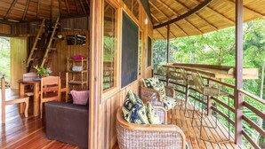 A wooden deck with wicker furniture and a staircase leading to an upper level. - Paradiselodge - Jungleguesthouse - next to Nauyaca (Platanillo de Baru)