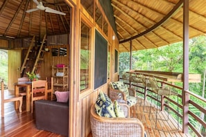 A wooden deck with wicker furniture and a staircase leading to an upper level.