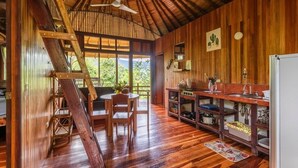 A wooden interior with a kitchen, dining area, and a staircase. - Paradiselodge - Jungleguesthouse - next to Nauyaca (Platanillo de Baru)