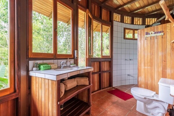 A wooden bathroom with a sink, mirror, and toilet.