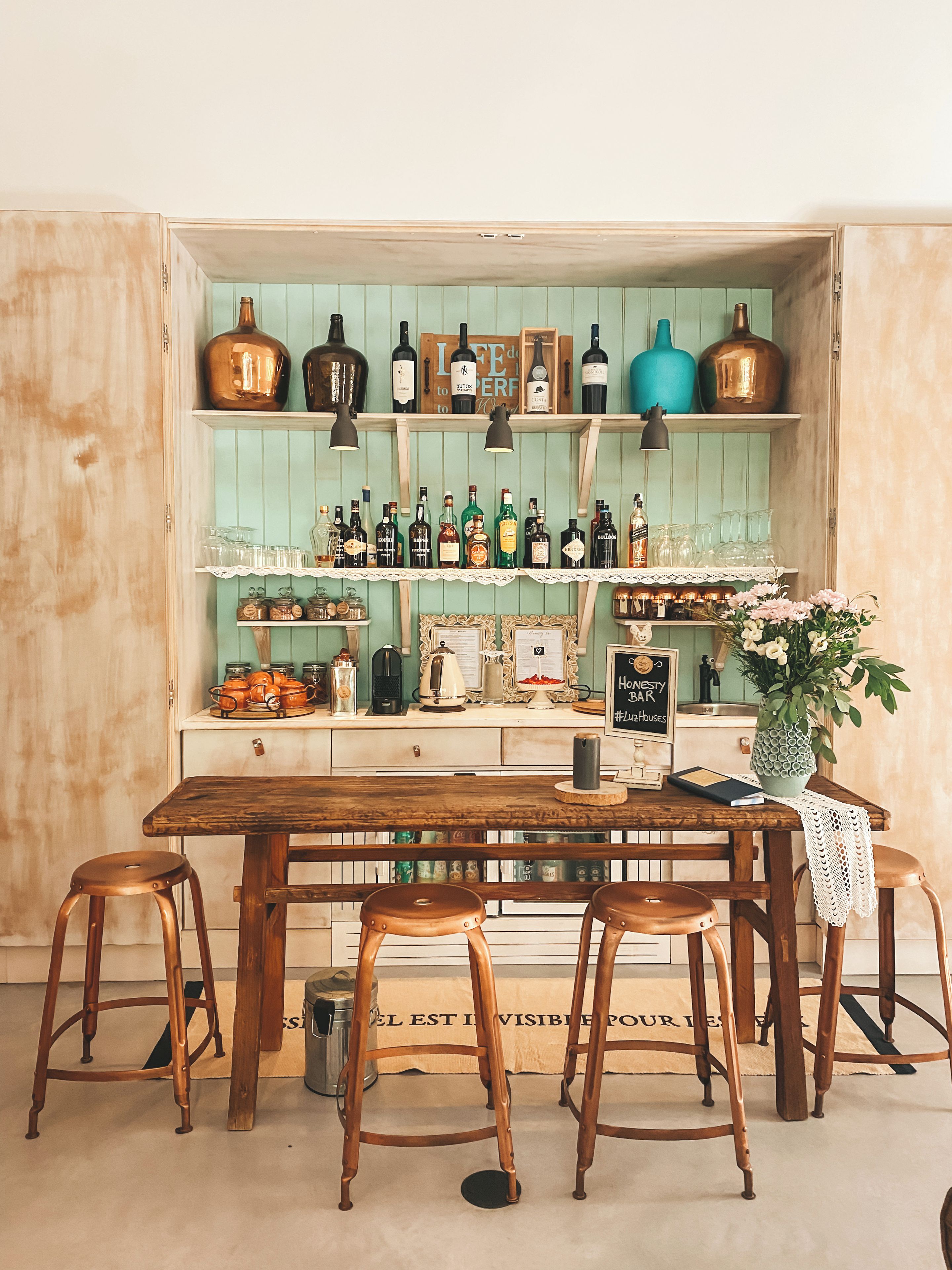 Un rústico espacio de bar con muebles de madera, estantes con botellas y una estética vintage.